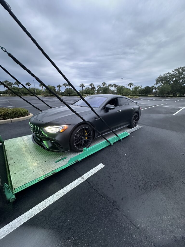 Mercedes being loaded Into the back of an enclosed transport trailer.