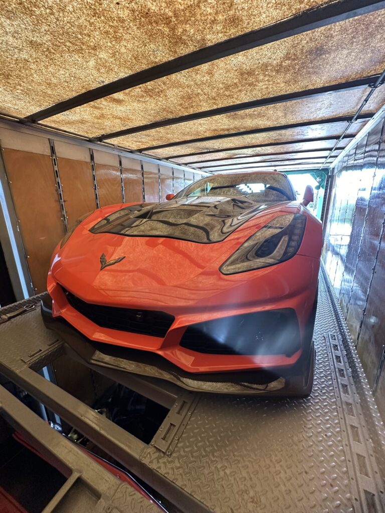 Corvette safely loaded into the back of an enclosed transport trailer.
